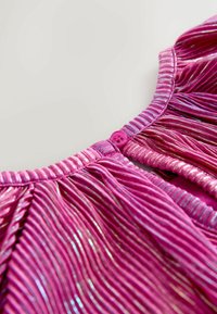 Rózsaszín, pliszélt anyag fémből készült szálakkal, kerek nyakkal és rózsaszín gombbal a hátsó záródáshoz. Függőleges vonalakkal texturált.