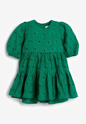 Robe en coton verte avec un col rond, des manches bouffantes et une jupe à volants. Présente des motifs de broderie en œillets sur l'ensemble.