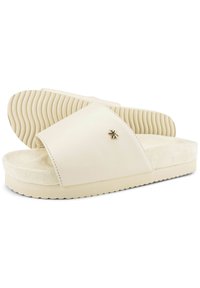 Beige slide sandals with a wide, smooth leather strap, a textured footbed, and a subtle gold star accent on the strap. Rubber outsole.