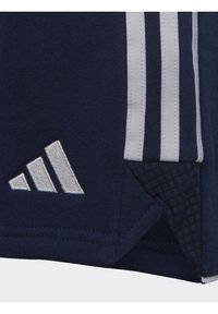 Marineblauwe sporttrui met contrasterende witte strepen, gestructureerde zoom en geborduurd wit logo in de linkerbenedenhoek.