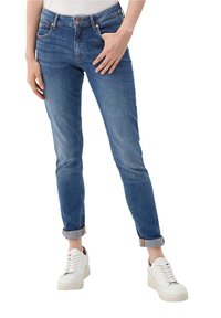 Blå denimjeans med slim fit, med uppvikta ben, fem fickor och knäppning. Bärs med vita sneakers.