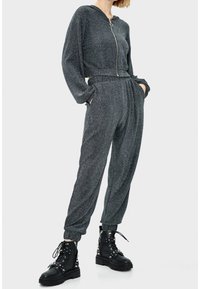 Czarny brokatowy dres z krótką bluzą na zamek i luźnymi spodniami. Połączony z czarnymi zasuwanymi butami bojowymi z nitami.