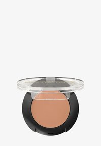 Poudre compacte avec un couvercle transparent et une base noire, présentant une surface lisse et marron clair. L'étiquette indique "MAX FACTOR X" en doré.
