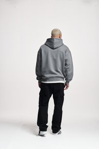 Grey oversized hoodie with a large hood, ribbed cuffs, and hem. Paired with black cargo pants featuring side pockets and a relaxed fit.