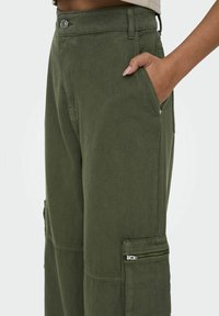 Olijfgroene cargobroek van duurzaam materiaal, met zijzakken, een bovenste knoopsluiting en een ritszakdetails.
