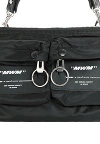 Bolso de mano de nylon negro con doble cremallera metálica, dos bolsillos delanteros y parches con el logo. Presenta una superficie texturizada y un asa corta de cuero.