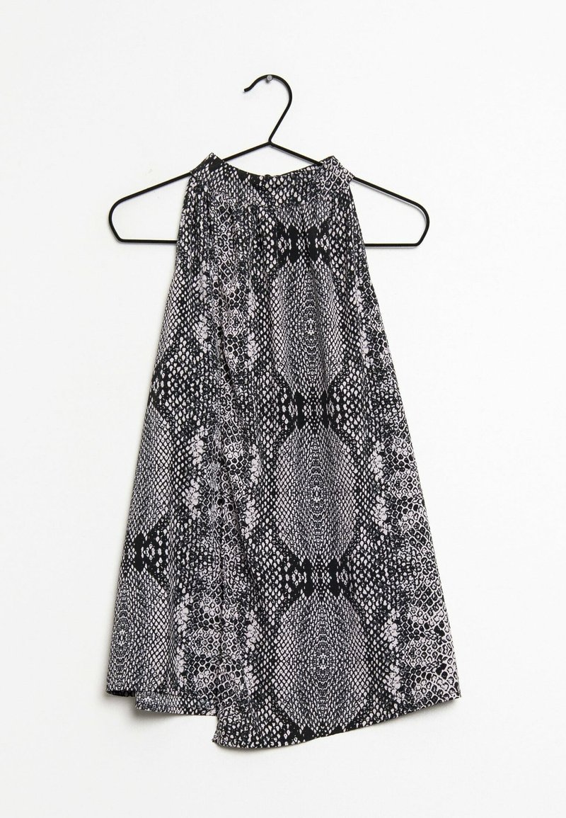 Haut dos nu noir et blanc avec un motif imprimé serpent, présentant un aspect texturé et un design fluide, suspendu à un cintre en métal noir.