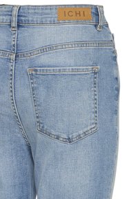 Jean en denim bleu clair montrant une poche arrière et un patch en cuir marron avec l'étiquette de marque "ICHI".