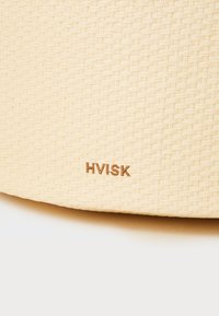 Beige woven bag with a textured finish. Features embossed "HVISK" logo in gold lower right. Sturdy, lightweight design suitable for casual use.