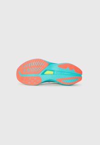 Sole of a sports shoe in turquoise with coral red and yellow accents, showing tread patterns and brand name "Saucony" in the center.