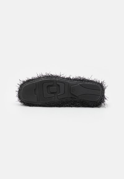 Black sneaker outsole with a textured rubber base and fuzzy black upper material, featuring a distinctive shaggy fringe around the edges.