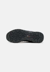 Semelle de chaussure de sport noire présentant un profil rugueux et texturé avec des crampons multidirectionnels; marquée du logo 'grip-ex' pour une meilleure adhérence.