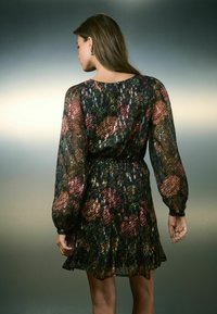 Blumenkleid mit langen durchsichtigen Ärmeln, einer taillierten Taille und einem fließenden Rock. Dunkler Hintergrund mit mehrfarbigen Blumenmustern in Rot und Grün.