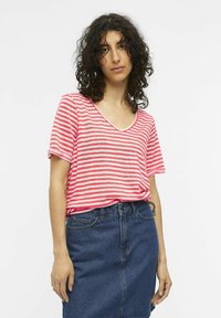 T-shirt en coton rayé rose et blanc avec un col en V et des manches courtes, associé à une jupe en jean foncé. Coupe légère et décontractée.