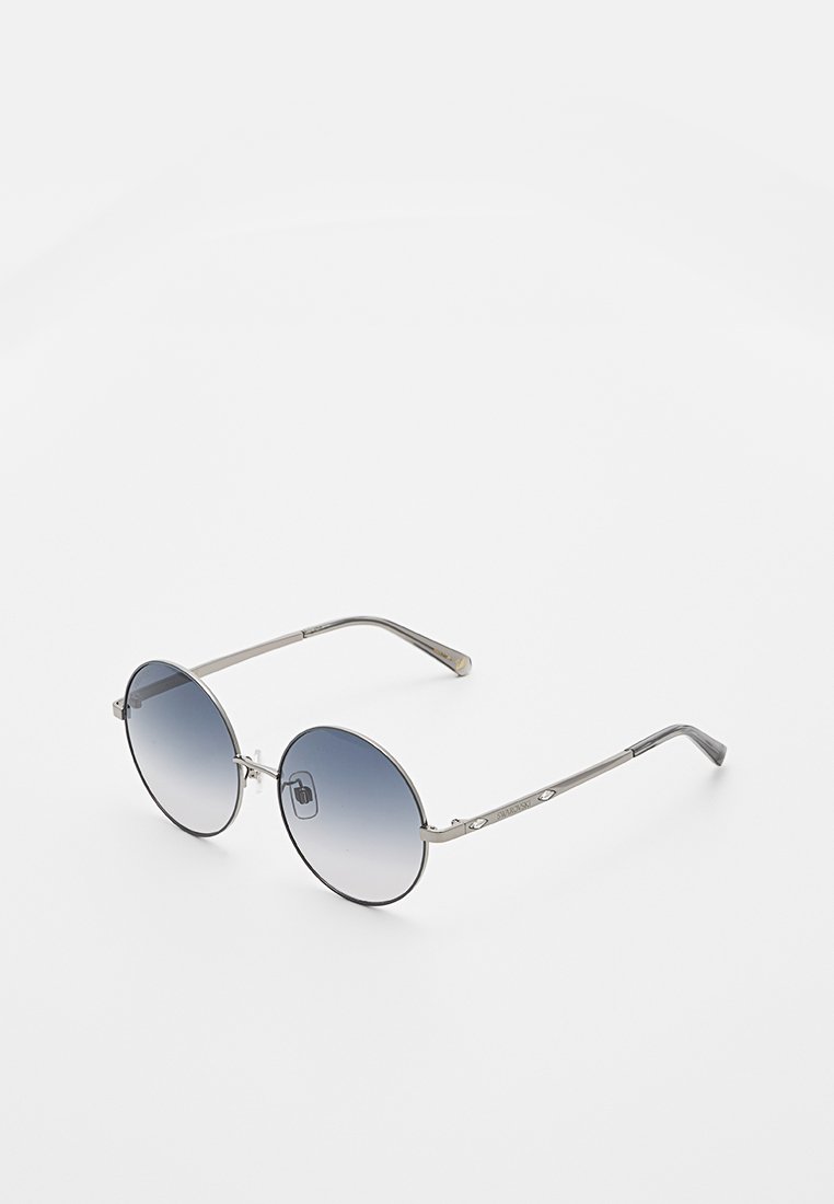Lunettes de soleil rondes avec des montures en argent fines et des verres dégradés bleus reposant sur une surface blanche.