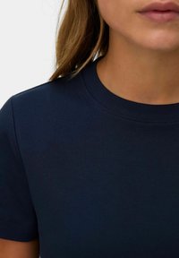 Mørkeblå bomulds t-shirt med rund hals, korte ærmer og en glat overflade. Har en subtil stræk og rene sømme.