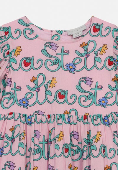 Roza dječja haljina s naboranim rukavima, ukrašena plavim rukopisnim tekstom "Stella" isprepletenim s šarenim cvijećem, jagodama i bubamarama.
