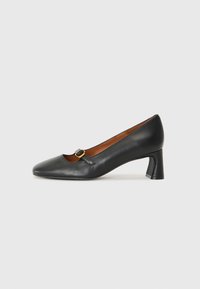 Black leather pump with a square toe, featuring a small cutout and a gold-tone buckle accent. Low block heel and smooth texture.