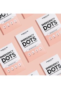 Emballage blanc avec texte noir, avec "POINTS D'URGENCE" pour couvrir les taches et imperfections. Fond rose clair, icônes mettant en avant les caractéristiques clés.