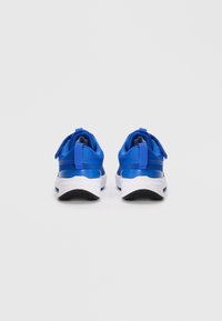 Des chaussures de sport bleues avec une tige en tissu lisse, une semelle intermédiaire blanche contrastante, une semelle extérieure en caoutchouc noir et des languettes au talon pour un enfilage facile.