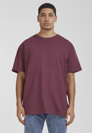 Bordo bombažna majica s krožnim izrezom, spušenimi rameni in kratkimi rokavi. V kombinaciji z svetlimi jeans hlačami z izblujenimi vzorci.