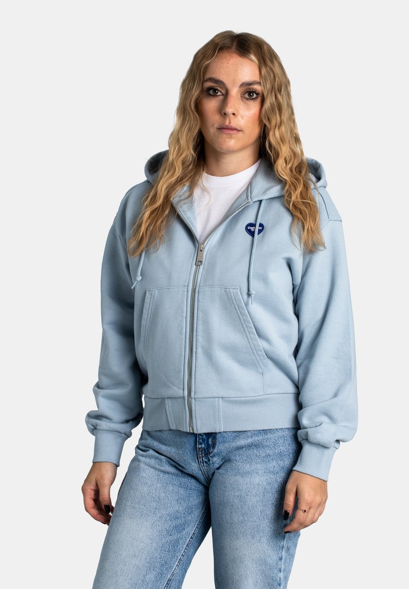 Felpa con zip di color azzurro chiaro, realizzata in tessuto morbido, con tasca frontale, cappuccio con cordino e logo ricamato sul petto.