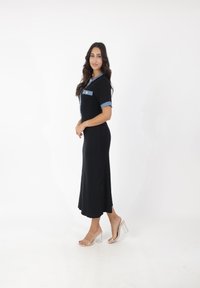 Zwart geribbeld midi-jurkje met denim kraag en korte mouwen, voorzien van een borstzak en transparante blokhak sandalen.