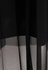 Zwarte gaasstof met een gelaagd ontwerp, met een gestructureerde textuur en transparante uitstraling. De stof is lichtgewicht met horizontale secties.