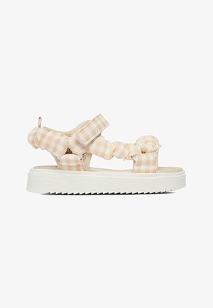 Sandale din material textil bej și alb cu model în carouri, cu bretele căptușite, închidere cu velcro, talpă groasă albă canelată și buclă la călcâi pentru încălțare ușoară.