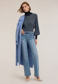 Modrý a černý pruhovaný top s dlouhým rukávem, světle modrý kabát, světle modré široké džíny a béžové vysoké podpatky. Hladké látky a přiléhavé tvary.