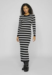 Svart och vit randig stickad klänning, långa ärmar, rund halsringning, slim fit, ribbad textur, sidoflikar, accentuerad med gyllene knappar på axlarna.