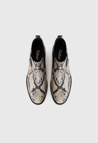 Poros slip-on auliniai batai su juodu ir smėlio spalvos gyvatės raštu, apvaliais pirštais ir juodais elastingais šoniniais paneliais lengvame fone.