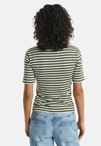 Grøn- og hvidstribet kortærmet t-shirt, lavet af bomuld, tætsiddende design, glat struktur, parret med lyseblå denimjeans.