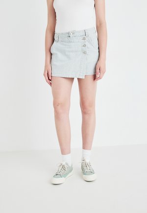Stripet denim mini-skjørt med fem knapper og en sidedel, kombinert med lysegrønne sneakers og hvite ankelstrømper.