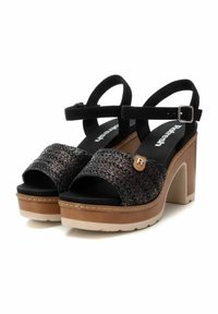 Sandali platform neri intessuti con fasce larghe, fibbia regolabile sulla caviglia e tacco spesso color marrone chiaro. Presentano una superficie strutturata.