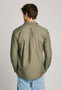 Camicia verde oliva a maniche lunghe con bottoni, dal fit rilassato, caratterizzata da una piega posteriore e polsini con bottone, realizzata in cotone morbido.