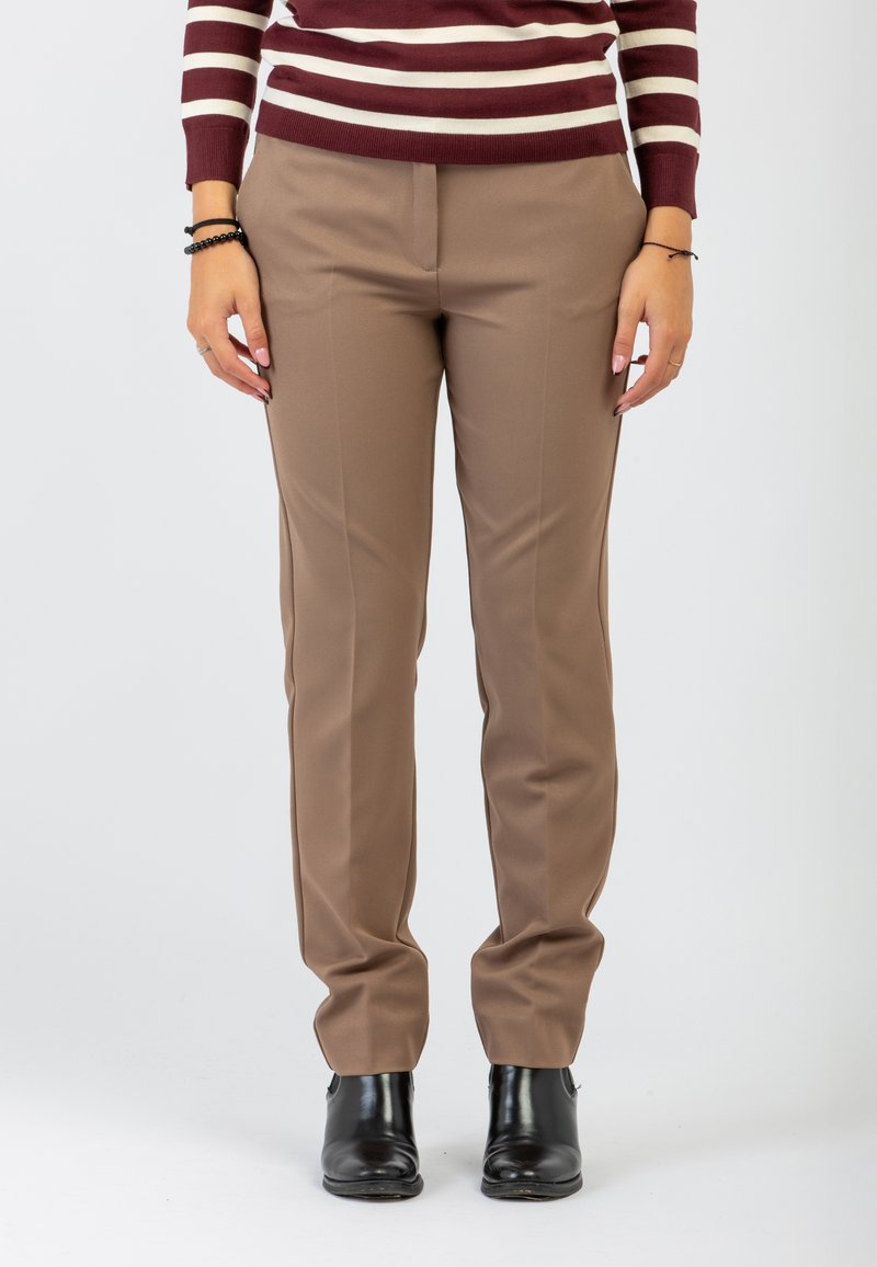 Pantaloni marroni su misura con piega frontale, tessuto liscio e tasche laterali. Indossati con stivaletti neri alla caviglia e un maglione a righe bordeaux.