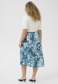 Une jupe midi avec un motif léopard abstrait bleu et blanc, fabriquée dans un tissu léger au toucher doux.