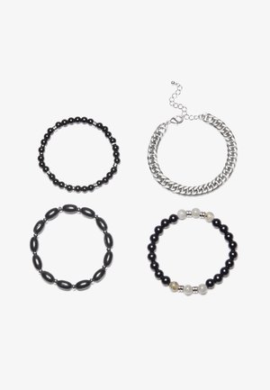 Quatro pulseiras: uma em corrente de prata e três com contas em preto, apresentando vários tamanhos e texturas de contas. Duas incluem acentos em prata, uma com contas claras.