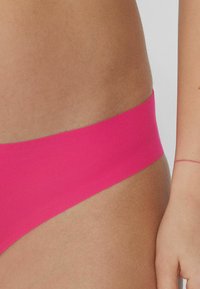 Parte inferior de bikini de natación rosa con una textura suave y una cinturilla ancha, que destaca un diseño minimalista y un color vibrante.