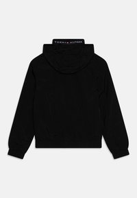 Zwarte jas met een capuchon, elastische manchetten en zoom. Voorzien van een gebrandmerkte kraag en een gladde, matte textuur. Eenvoudig, functioneel ontwerp.