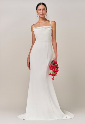 Robe de mariée en satin blanc avec un décolleté en cœur et des fines bretelles, présentant une silhouette cintrée qui se prolonge en une légère traîne.