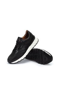 Zapatillas deportivas negras con parte superior de cuero texturizado, paneles de malla y suelas de goma blancas. Presenta cordones redondos y detalles de costura.