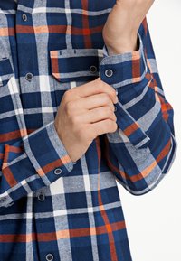 Camicia a quadri blu e bianca con linee arancioni, realizzata in un tessuto strutturato. Presenta polsini con bottoni e una tasca sul petto.