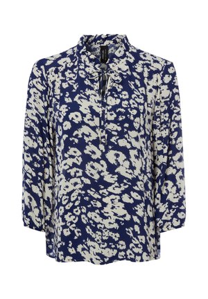 Blouse bleu marine à manches longues avec imprimé floral abstrait blanc et petit col à volants noué au niveau de l'encolure.