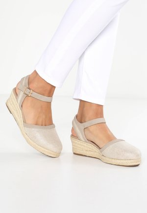 Beżowe koturny espadryle o tkanej fakturze, z odkrytymi plecami i paskiem wokół kostki. Podeszwa wykonana z naturalnego juty zapewnia lepszą przyczepność.