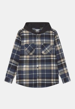 Chemise à manches longues à carreaux bleu, beige et noir, boutonnée, avec deux poches poitrine et une capuche noire.