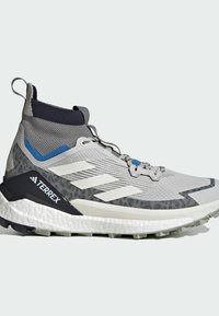 Buty trekkingowe Terrex w szarym kolorze z czarnymi i niebieskimi akcentami. Posiadają chropowatą cholewkę, zapięcie na sznurowadła oraz wytrzymałą, wzorzystą podeszwę zapewniającą przyczepność.