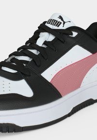 Μαύρο, άσπρο και ροζ αθλητικό παπούτσι Puma με μαύρα κορδόνια και λογότυπο ορατό στη λευκή γλώσσα, σε λευκό φόντο.