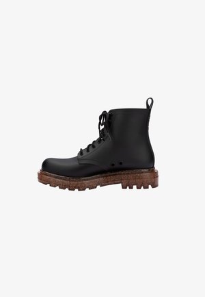 Zwarte veterschoenen tot de enkel met een gladde, matte afwerking, chunky bruine zool en zijsnijdingen voor ventilatie. Ontworpen voor duurzaamheid en stijl.